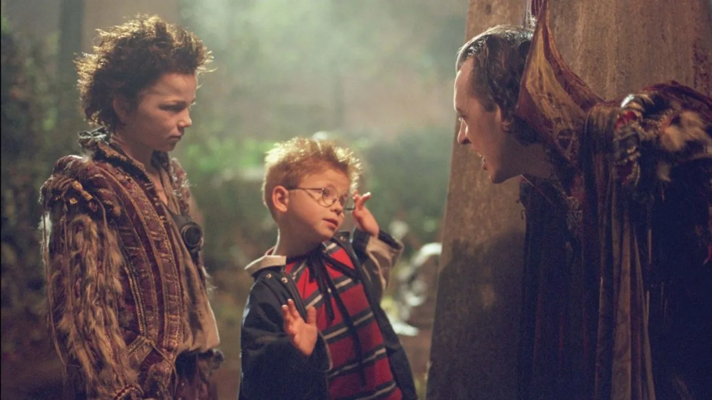Film still of two boys and a man in a dark, misty wood
